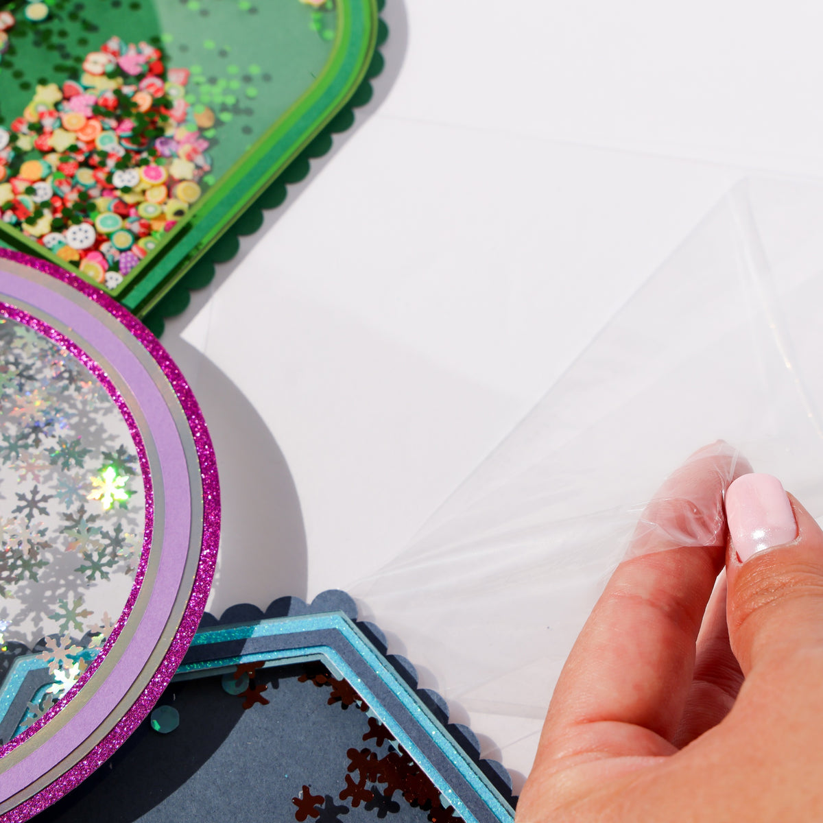 Peeling the protective film off a clear acetate sheet, next to finished shaker cards