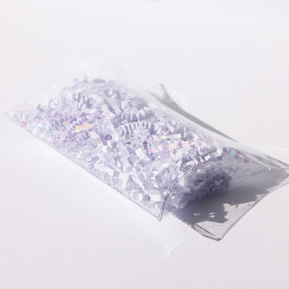 Clear acetate pillow box filled with white and iridescent paper shred, a party favor made from acetate sheets