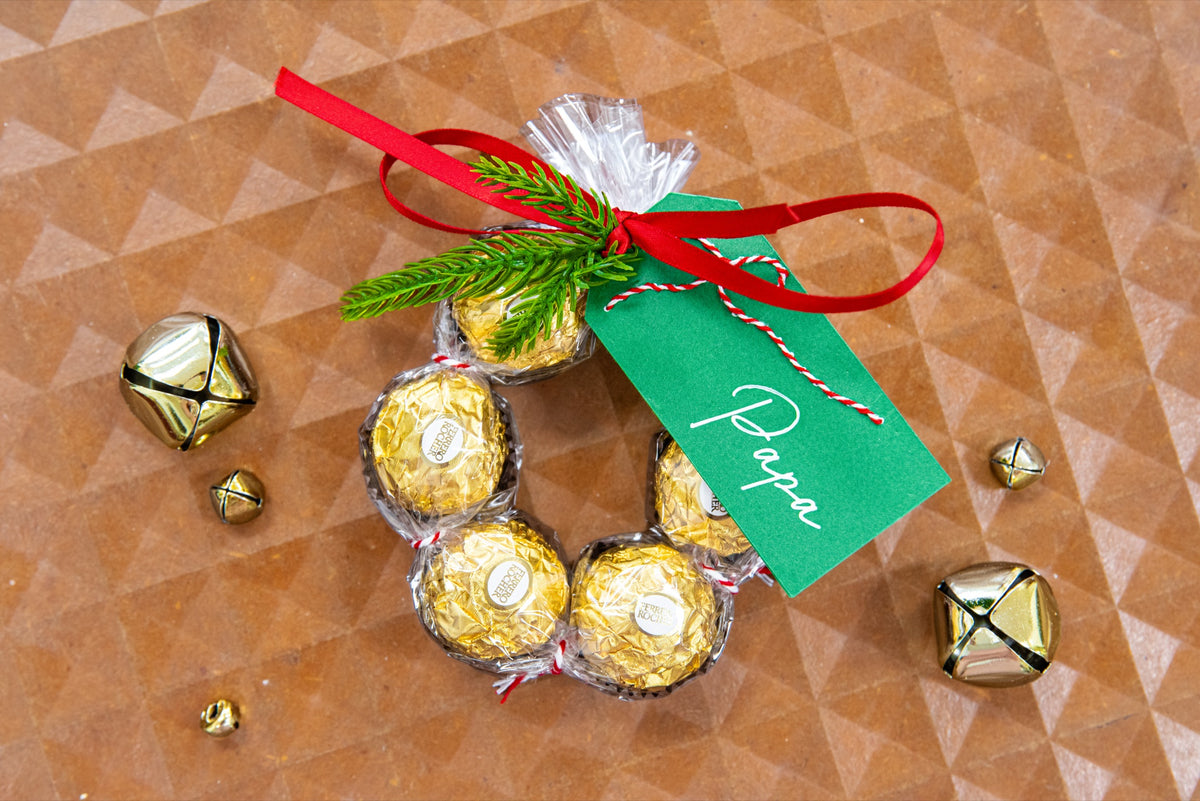 Hand embroidered dark green cardstock Christmas gift tag stitched with a name on a chocolate treat wreath