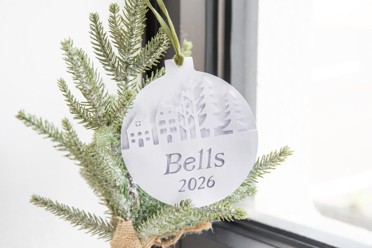 Personalized layered paper ornament with a winter village scene, name, and year cut from white cardstock