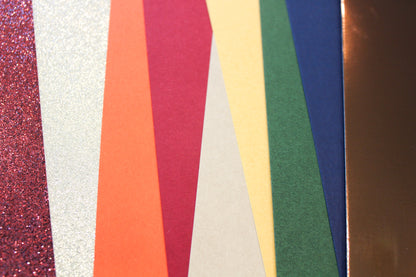 Fanned fall cardstock sheets in dark orange, merlot, goldenrod, pine green, and deep blue