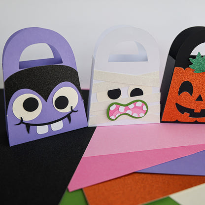 Vampire, mummy, and glitter pumpkin boo bags lined up on Halloween cardstock