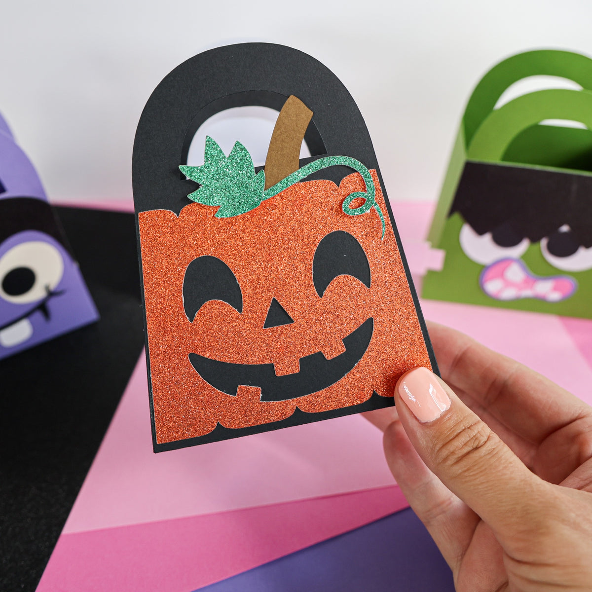 Glitter jack-o-lantern boo bag held in hand showing the finished Halloween treat bag size