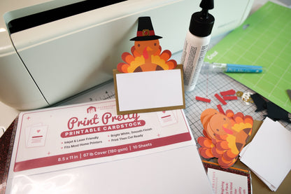 Turkey place card with a Pilgrim hat next to a pack of printable cardstock