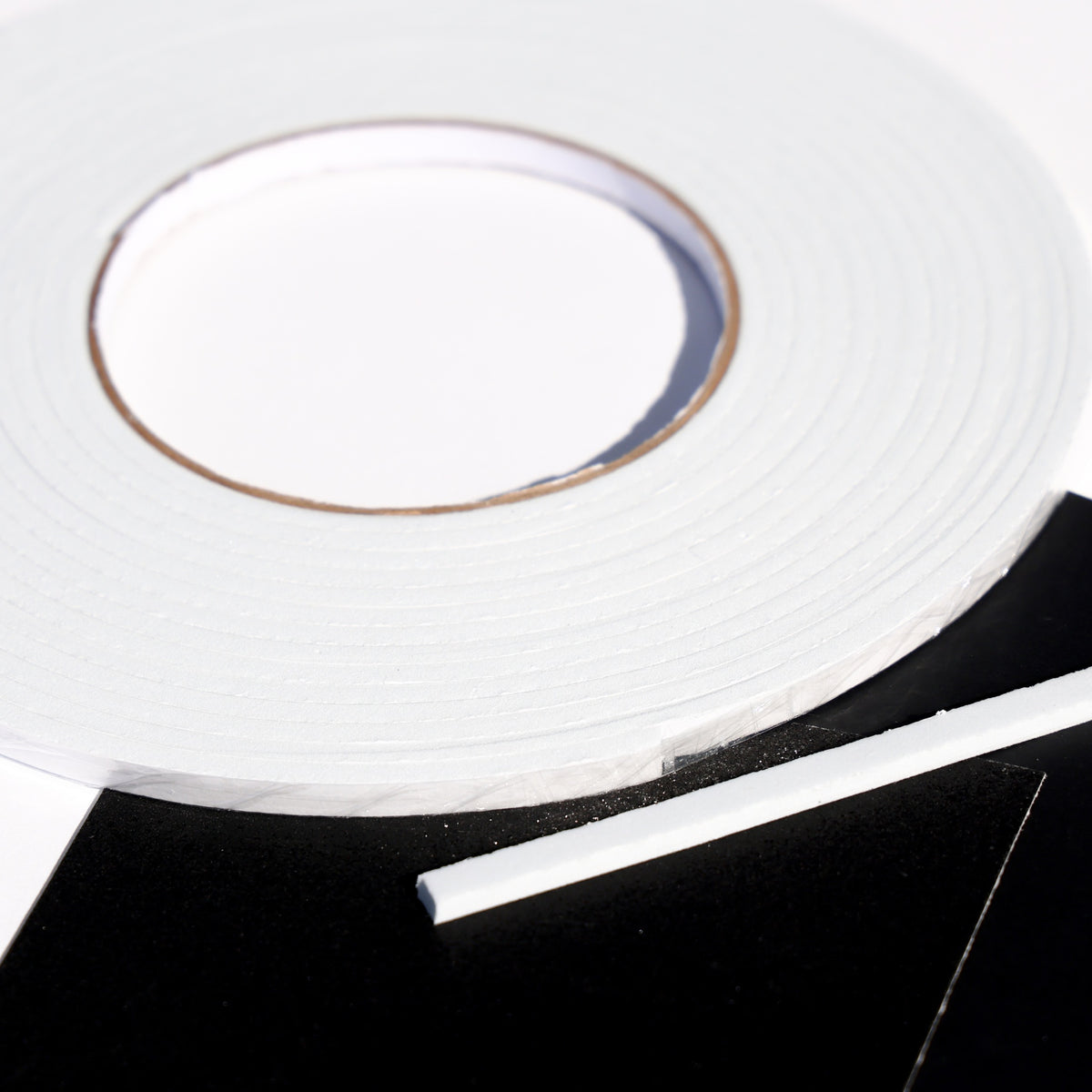 White double sided 3D foam tape roll with a cut strip on black cardstock for layered card making