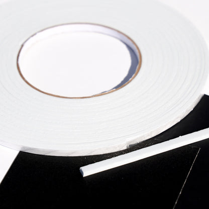 White double sided 3D foam tape roll with a cut strip on black cardstock for layered card making