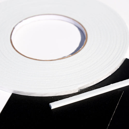 White double sided 3D foam tape roll with a cut strip on black cardstock for layered card making